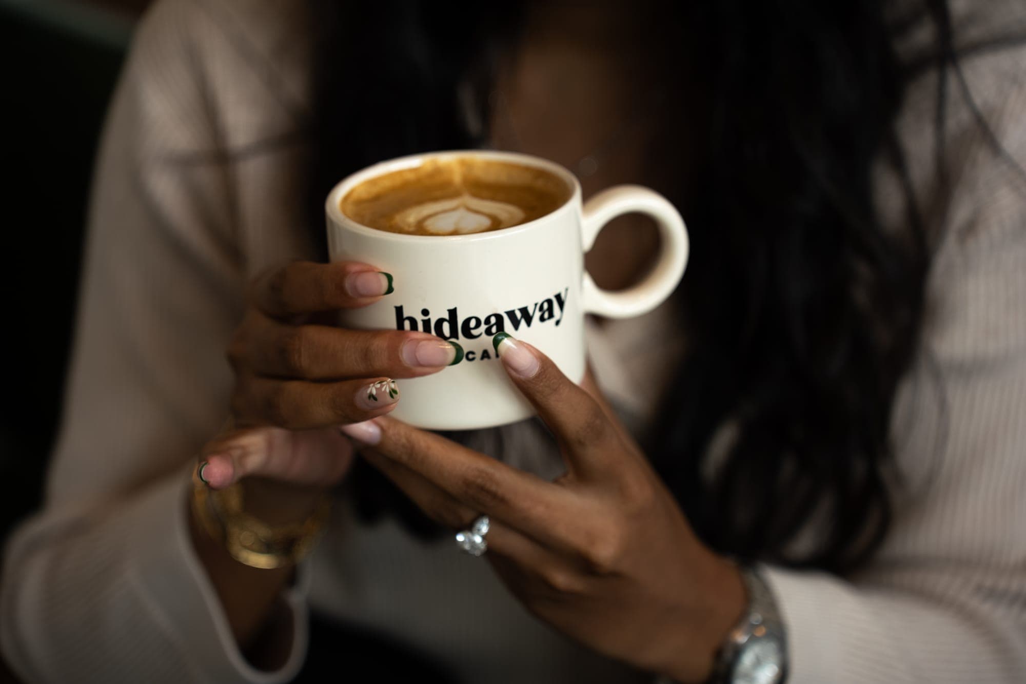Two hands holding a hideaway mug of latte